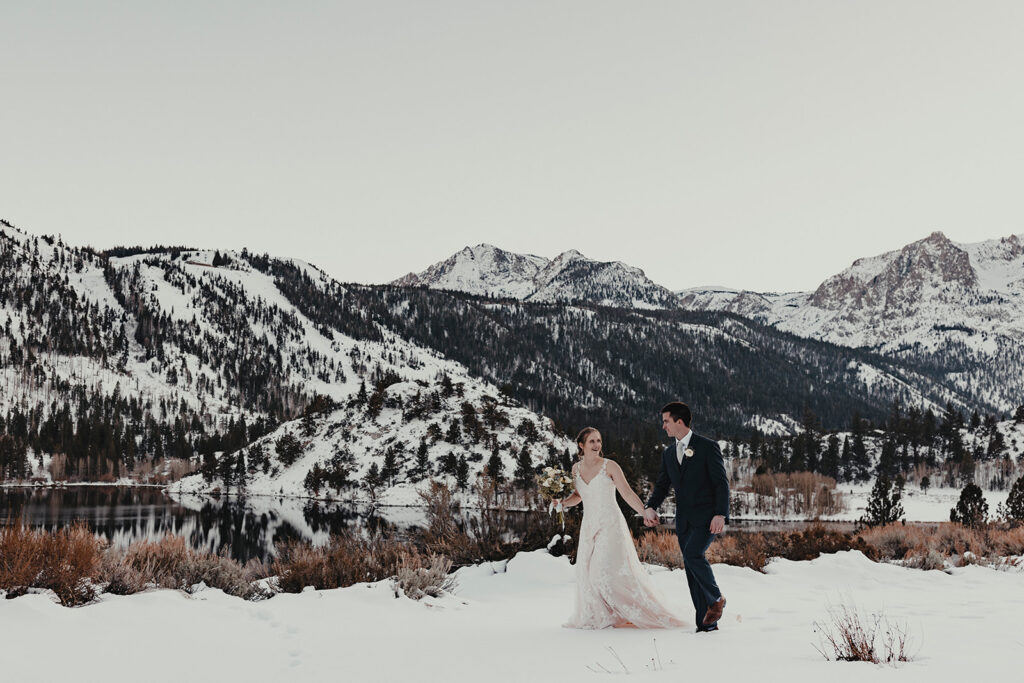 A bride and groom walking through the snow in June Lake California